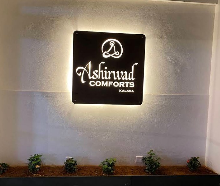 Illuminated Ashirwad Comforts signage in the hotel lobby, Kalasa